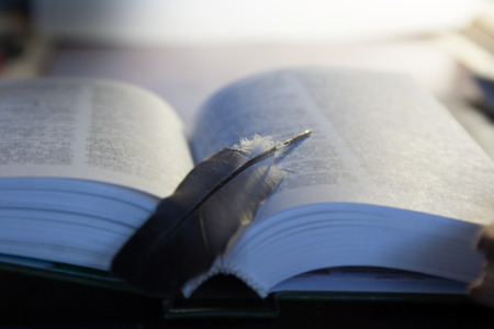 open book and quill pen on a tableの写真素材