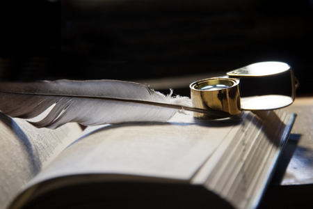 Close-up of open book, quill pen  and magnifying glassの写真素材