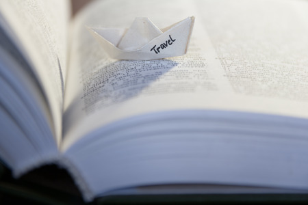 Travel concept, paper boat with inscription travel and open bookの写真素材
