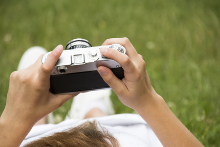 girl holding vintage camera against green meadowの写真素材