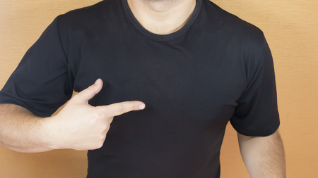 Man with muscular torso pointing his finger on a blank tshirtの写真素材