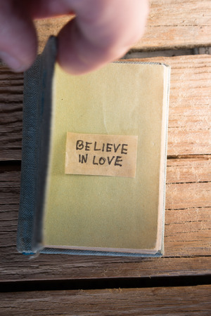Believe in love concept. label and open book on the wooden background.の写真素材