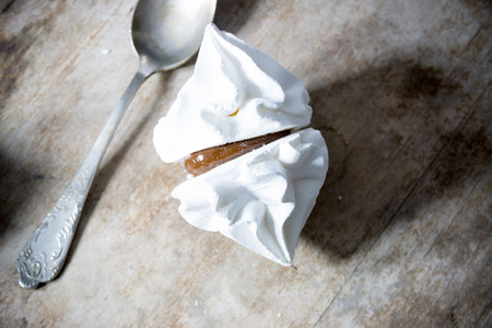 white meringue on a wooden surface and spoon, overeating , obesity, sweet tooth ideaの写真素材