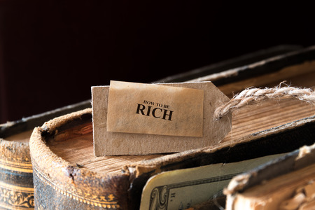 How To Be Rich Concept. Old books, inscription and money, toned, vintage.の写真素材