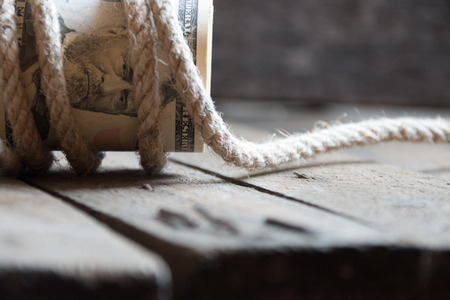 American Fifty Dollar Bills rolled up and rope on a wooden tableの写真素材