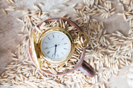 harvest time, gold pocket watch and oat grain on the tableの写真素材