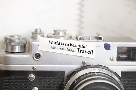 Vintage photo camera and text  'World is so beautiful, take me and let's go travel!'の写真素材