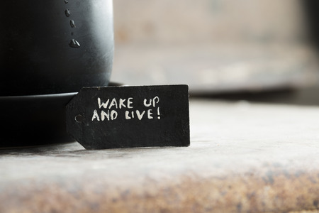 wake up and live tag and a cup of coffee on the tableの写真素材