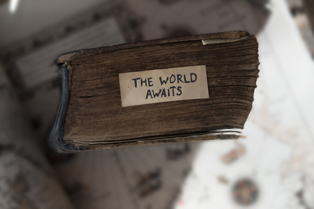 Traveler idea. The World Awaits text, old book and old geographic map Jan Huyghen van Linschoten 1599.の写真素材
