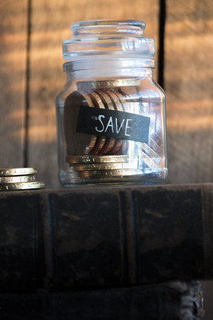 Save idea, gold coins in a glass jar,  inscription save and a stack of gold coins on the sunset.の写真素材