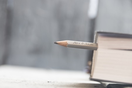 Back to school concept. A pencil and a book on the table, back to school inscription in pencil.の写真素材