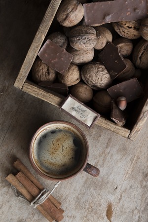 good morning text and a cup of coffee, chocolate and nuts on the tableの写真素材