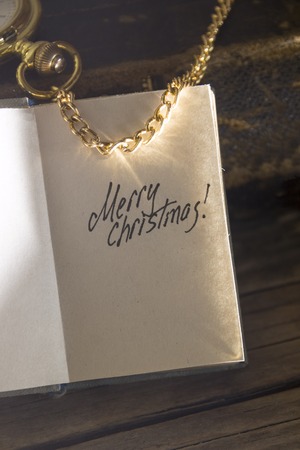 Merry Christmas - inscription, gold pocket watch and old vintage book.の写真素材