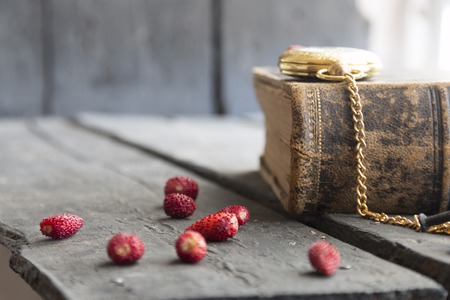 food background - strawberry on a vintage table, pocket watch and bookの写真素材