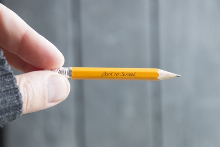 hand holding a pencil, Back to School - written in pencilの写真素材