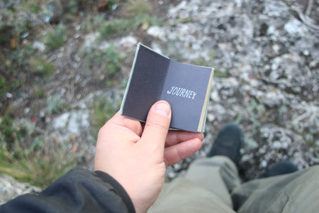 Hand holding a book with the inscription Journey.