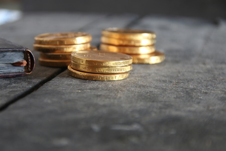 Golden coins and a book on the old vintage wooden table.の写真素材