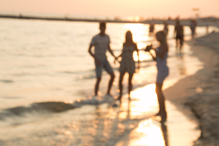 Silhouettes of young group of people in ocean at sunset. blurry photo. Summer Holiday Vacation Concept.の写真素材