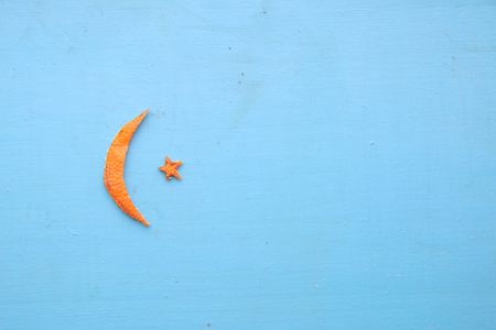 Crescent moon and star for Ramadan. Tangerine peel on the table.の写真素材