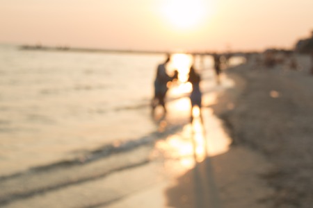 Silhouettes of young group of people in ocean at sunset. blurry photo. Summer Holiday Vacation Concept.の写真素材