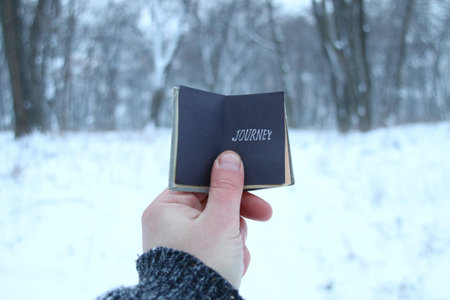 Journey idea. Traveler holds a book in his hand with the inscription. Blurred photos for the...