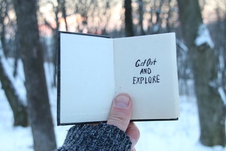 Get out and explore text. Travel idea. Book with an inscription, snowy winter parkの写真素材