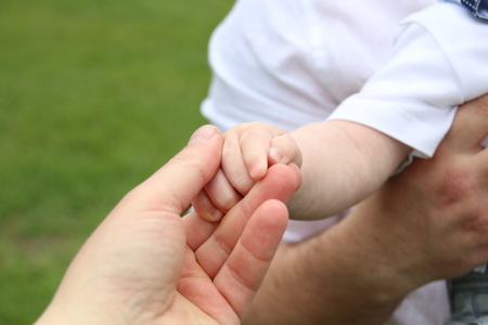 Closeup of baby hand into parents hands.の写真素材