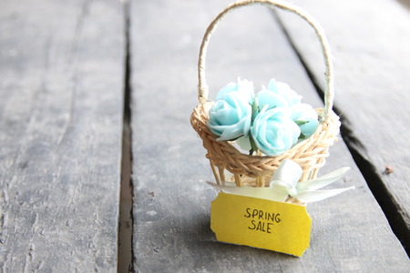 Spring sale tag and flowers in a small basket, copy space. Composition on the old table.の写真素材