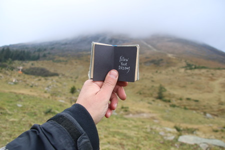 journey - travel concept, traveler holds a book with an inscription - follow your dreamsの写真素材