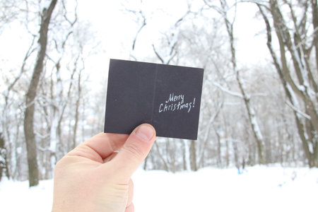 hand holding a christmas card with inscription merry christmas