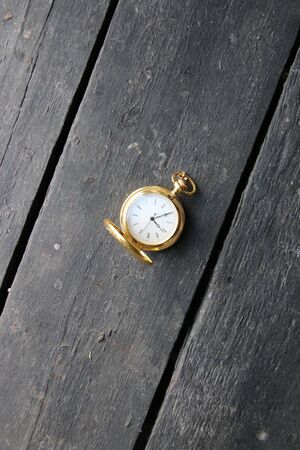Time management idea. Golden pocket watch on a vintage table.の写真素材