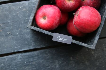 Grocery online shop idea. Ripe red apples in wooden box and tag with the inscription online.の写真素材