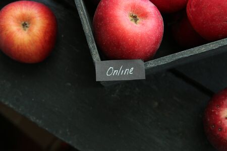 Internet, web service idea or Grocery online shop concept. Ripe red apples in wooden box and tag with the inscription online.の写真素材