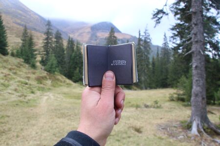 journey - travel concept, traveler holds a book with an inscriptionの写真素材