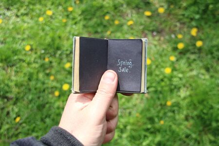 Text in a book. On the background spring grass and yellow wildflowersの写真素材