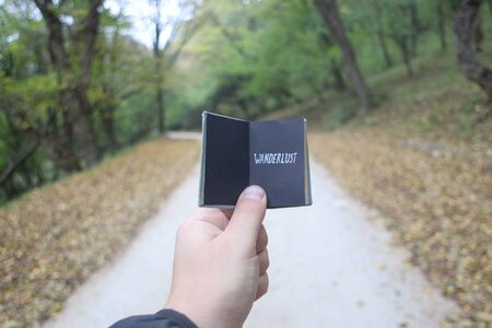 wanderlust idea, hand holding a book with textの写真素材