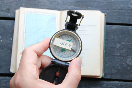 Pointer to the sea and an old compass. Summer tour at sea concept.