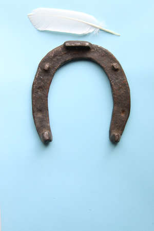 horseshoe and white feather on a blue backgroundの写真素材