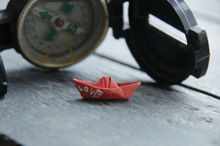 Search for love concept. Navigational Compass and a paper boat with the inscription loveの写真素材