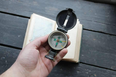 Hand Holding Navigational Compass on vintage map backgroundの写真素材