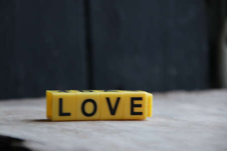 The word love made of yellow letters on a wooden background.の写真素材
