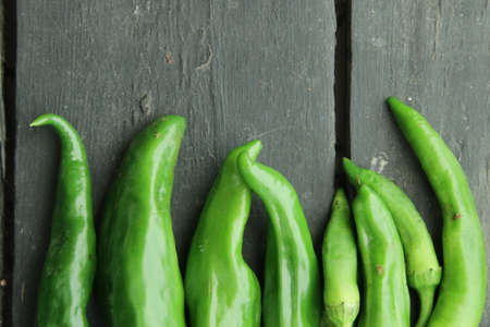 Green hot pepper in wooden plate closeup. Food photographyの写真素材