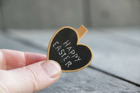 Happy easter concept. The hand holds a heart with the inscription.の写真素材