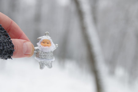 Hand holds santa claus on the background of the winter forest.の写真素材