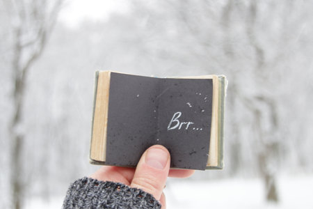 Cold Weather idea. Shows low temperatures concept. A hand holds a book with the inscription.の写真素材
