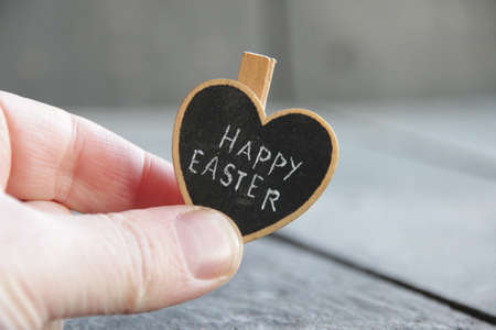 Happy easter concept. The hand holds a heart with the inscription.の写真素材