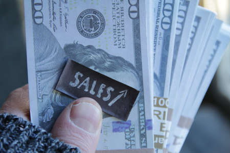 Sales growth concept. Hand holds bundles of moneyの写真素材