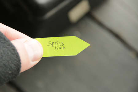 Spring time. The hand holds a tag with a handwritten inscription.の写真素材