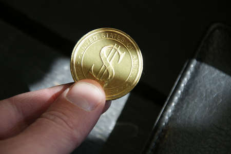 The hand holds a golden dollar coin. Successful business.の写真素材