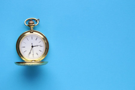 Golden retro pocket watch on a blue background.の写真素材